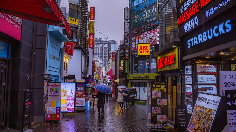 명동 쇼핑 거리의 간판과 비 내리는 저녁 풍경